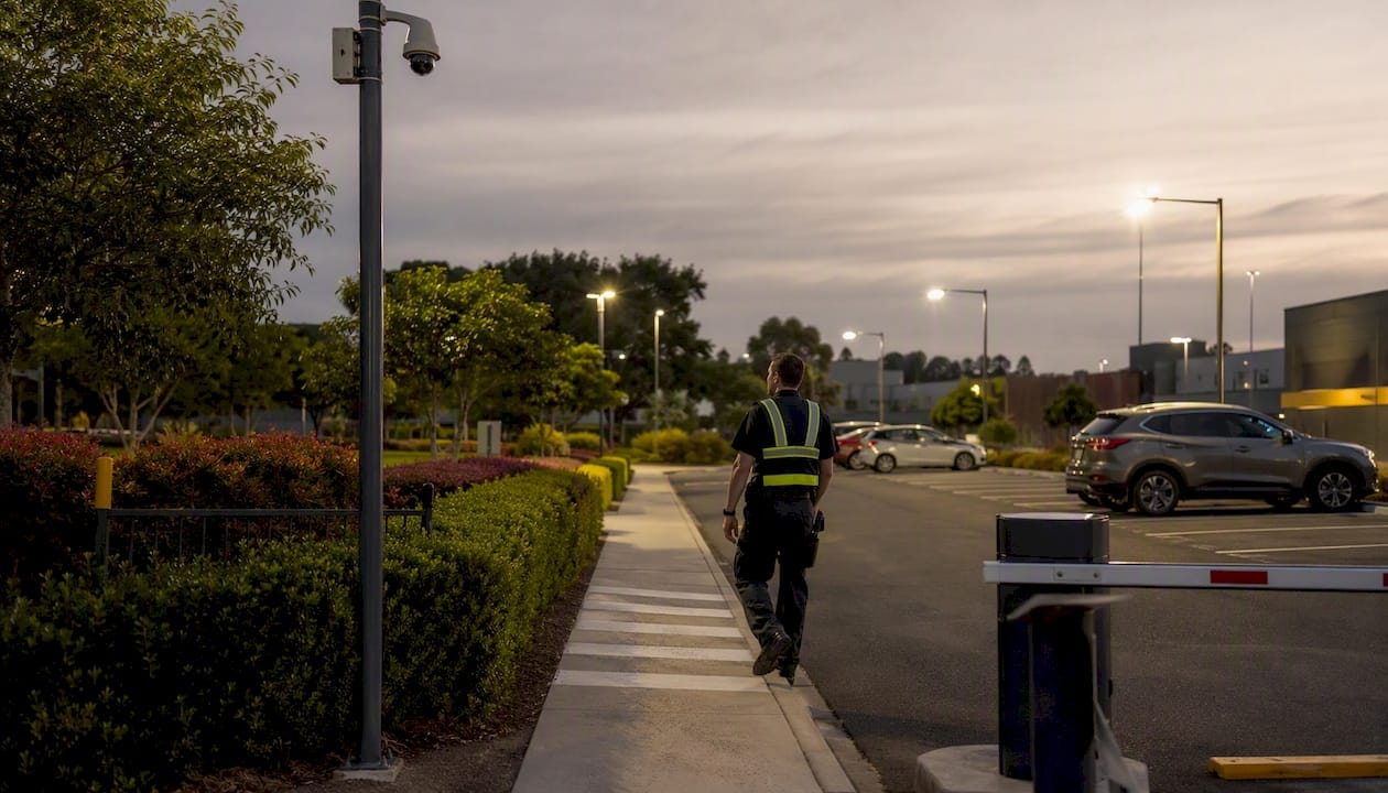Security guard patrolling illuminated car park entry